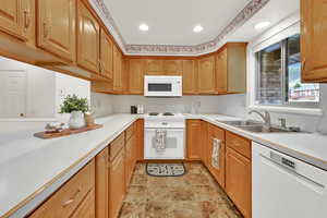 Kitchen with light countertops, white appliances, stone finish floors, recessed lighting, and wood finish cabinets