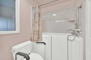 Bathroom with toilet and shower / bathtub combination with curtain