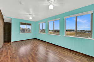 Spare room with ceiling fan, dark wood-style flooring, wooden walls, and a smoke detector