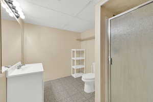 Bathroom with a paneled ceiling, vanity, a shower stall, and light tile patterned floors