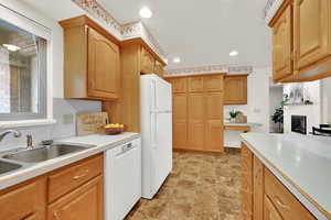 Kitchen with white appliances, light countertops, recessed lighting, a fireplace, and stone finish flooring
