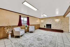 Living area featuring wooden walls, a wainscoted wall, a fireplace, and ornamental molding