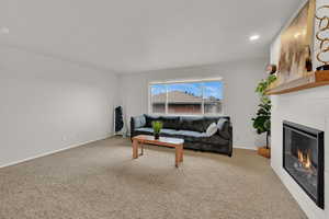 Living area with light carpet, a glass covered fireplace, and recessed lighting