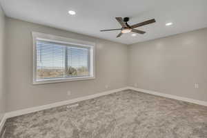 Carpeted empty room featuring a ceiling fan and recessed lighting