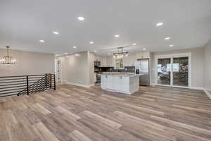 Kitchen featuring hanging lights, stainless steel appliances, open floor plan, and a kitchen island
