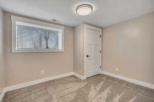 Empty room featuring light colored carpet and a textured ceiling