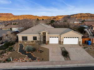 Ranch-style home with a garage, driveway, stone siding, stucco siding, and a mountain view