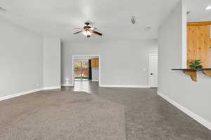 Unfurnished living room featuring a ceiling fan, dark tile patterned floors, and a textured ceiling