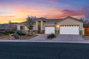 Ranch-style house featuring an attached garage, driveway, stucco siding, stone siding, and a tile roof
