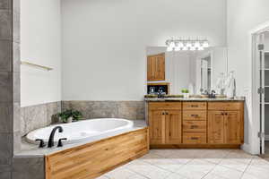 Bathroom with light tile patterned flooring, double vanity, and a garden tub