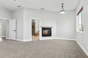 Unfurnished living room featuring light colored carpet and a multi sided fireplace