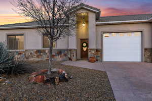 View of front of home featuring a garage, a tile roof, stucco siding, and stone siding