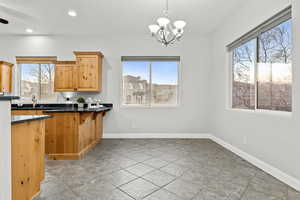 Kitchen with dark stone countertops, a chandelier, and a peninsula