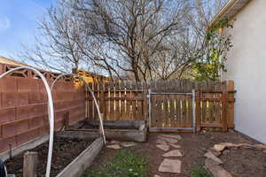 Fenced yard featuring a gate and a vegetable garden