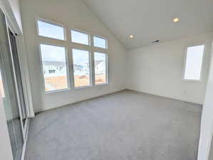 Primary bedroom with light colored carpet, recessed lighting, and lofted ceiling
