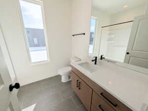 Upper Full bath with vanity, dark tile patterned floors, and a shower