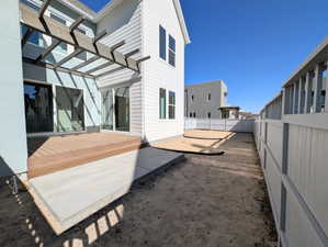 Back of property featuring a fenced backyard, a deck, a pergola, and a patio area