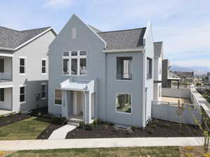 View of front of property with stucco siding, roof with shingles, a balcony, and a fenced yard