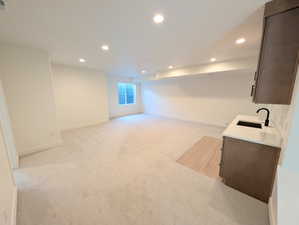 Basement living room with wet bar, recessed lighting and light carpet