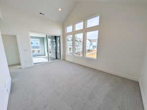 Primary bedroom with access to covered balcony featuring light carpet, vaulted ceiling, and recessed lighting