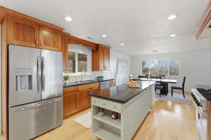 Kitchen featuring stainless steel appliances, light wood-style flooring, open shelves, and dark stone counters
