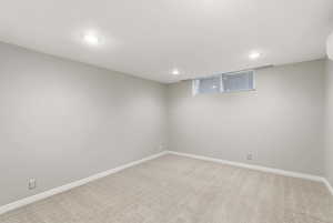 Finished below grade area featuring light colored carpet and recessed lighting