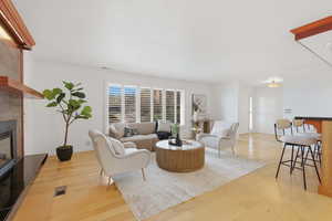 Living room featuring light wood-type flooring, a tile fireplace, and plenty of natural light