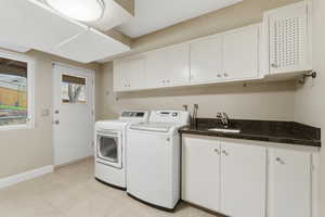 Laundry room featuring cabinet space, independent washer and dryer, and light tile patterned flooring