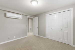 Unfurnished bedroom with light colored carpet, a mini split for heating / cooling, and a closet