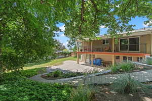 Rear view of property featuring brick siding, a patio, and a balcony