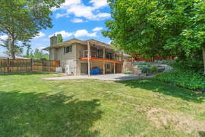 Back of house with a patio area, a balcony, a chimney, brick siding, and a fenced backyard