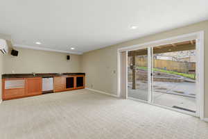 Indoor wet bar with light carpet, dark countertops, and recessed lighting