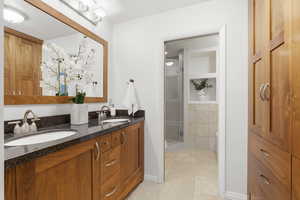 Full bathroom featuring double vanity, light tile patterned floors, and a stall shower