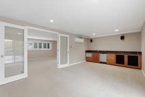 Indoor wet bar featuring dark countertops, light carpet, wood finish cabinetry, recessed lighting, and dishwasher