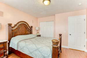 Bedroom featuring light wood-style floors, a closet, and a textured ceiling
