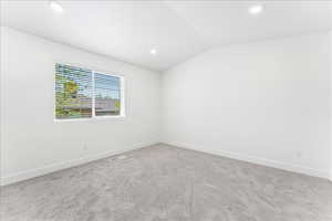 Carpeted spare room featuring lofted ceiling and recessed lighting