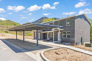 View of front of property featuring brick siding, a mountain view, and covered parking