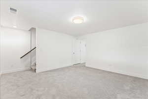 Unfurnished room featuring light colored carpet and stairs