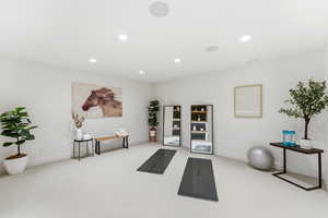 Exercise room with light carpet and recessed lighting
