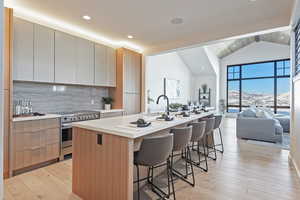 Kitchen featuring two tone cabinets, electric stove, a breakfast bar area, modern cabinets, and light wood-style flooring