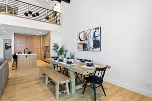 Dining area featuring light wood-style floors, recessed lighting, and a high ceiling