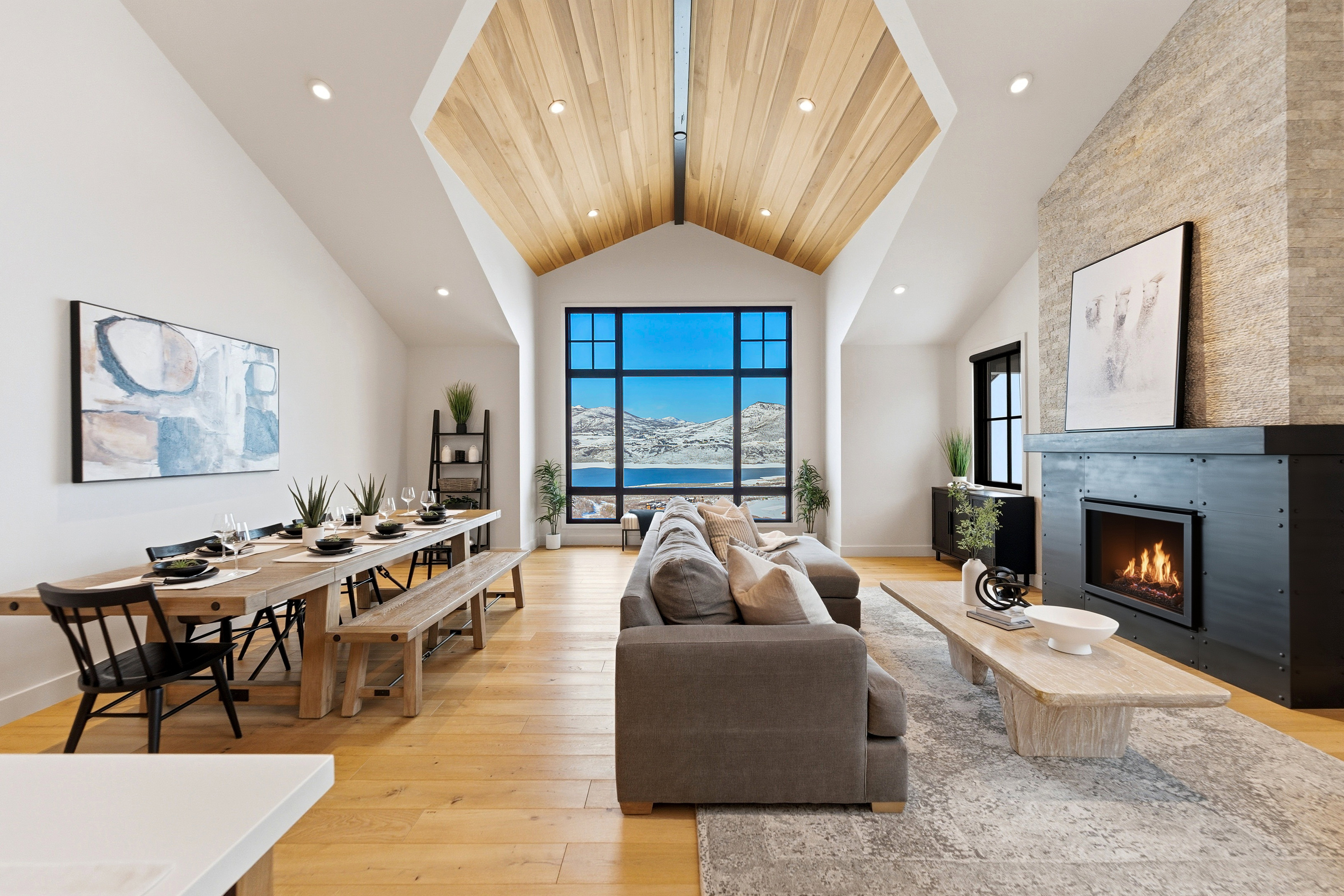Living room with a lit fireplace, light wood-type flooring, a high ceiling, and recessed lighting