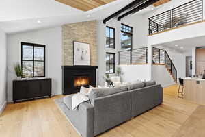 Living area with light wood-style flooring, a stone fireplace, recessed lighting, and vaulted ceiling