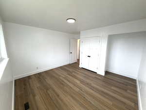 Unfurnished bedroom featuring dark wood-style floors and a closet