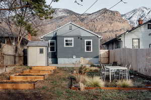Rear view of property featuring a fenced backyard, a vegetable garden, outdoor dining area, and a mountain view