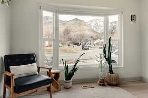 Sitting room with a mountain view, bay window, and light wood flooring