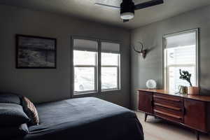 Bedroom with multiple windows, wood floors, and ceiling fan