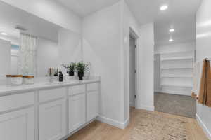 Bathroom featuring recessed lighting, a spacious closet, vanity, and light wood-style flooring