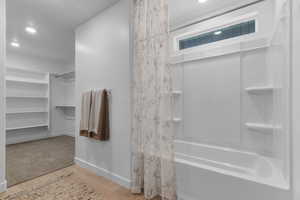 Bathroom with a walk in closet, light wood-style flooring, shower / bath combo, and recessed lighting