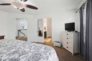 Bedroom with dark colored carpet, ceiling fan, and ensuite bath